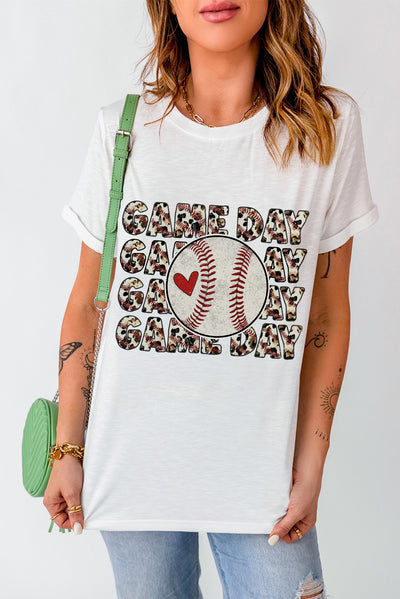 Woman wearing a GAME DAY round neck short sleeve t-shirt with baseball graphic, paired with jeans and a green bag.