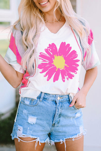 Woman wearing Daisy Graphic V-Neck Half Sleeve T-Shirt with vibrant pink daisy print, paired with distressed denim shorts.