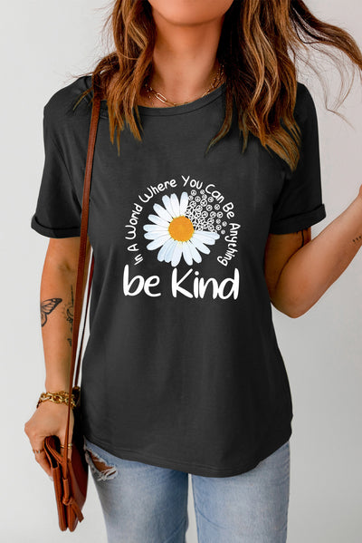 Woman wearing graphic round neck short sleeve t-shirt with "be kind" daisy design