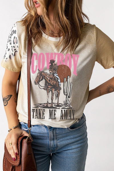 Woman wearing graphic round neck short sleeve T-shirt with cowboy design, styled with blue jeans and a brown leather bag.