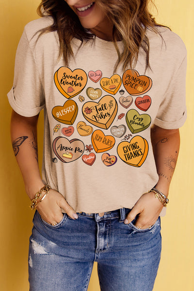 Woman wearing heart graphic round neck t-shirt with ripped jeans, featuring fall-themed hearts and text designs.