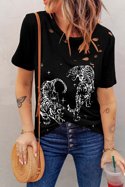 Woman wearing a black cutout graphic round neck short sleeve T-shirt with tiger design, paired with jeans and a woven purse.