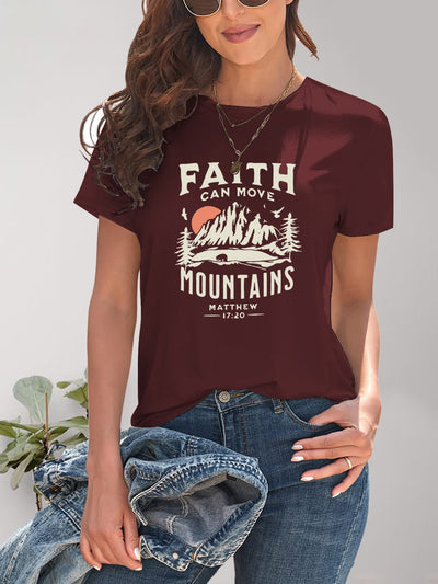 Woman wearing a maroon graphic round neck short sleeve T-shirt with a "Faith Can Move Mountains" design, paired with jeans and a necklace.