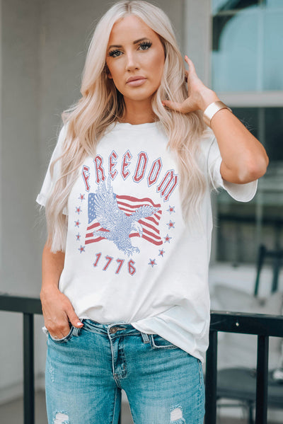 Woman wearing FREEDOM 1776 graphic tee with eagle and flag design, casual chic style, short sleeves, perfect for everyday wear.